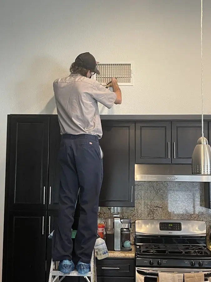 Technician inspecting an air vent during HVAC service in Covington